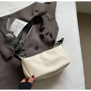 Détail du sac sous l'aisselle blanc cassé en cuir grainé avec large bandoulière noire