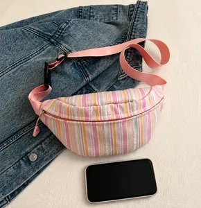 Confronto dimensioni della borsa a tracolla in nylon a righe accanto a un telefono