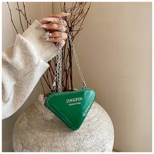 Makroaufnahme der grünen Dreieck-Tasche aus Lackleder mit Silberkette und Glanzeffekt