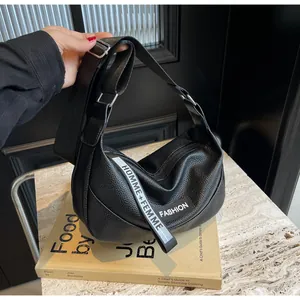 Détail du sac à bandoulière en cuir grainé avec sangle large et sangle en tissu lettré