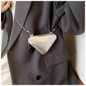Detailansicht der silbernen Dreieckstasche mit Metallkette auf grauem Anzugmodell