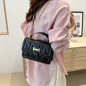 Sac à bandoulière matelassé noir chic avec chaîne dorée et boucle H porté par mannequin