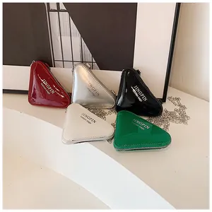 Draufsicht auf fünf bunte, glänzende Mini-Taschen in Dreiecksform mit feinen Ketten