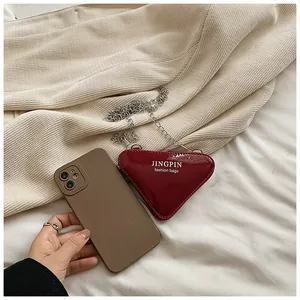 Makroaufnahme einer roten herzförmigen Mini-Tasche aus Lackleder mit einer silbernen Kette