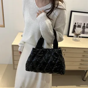 Detail of glossy black quilted space cotton tote bag held by female model in cozy room