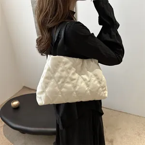 Close-up of quilted white puffer handbag featuring black straps and lattice stitching