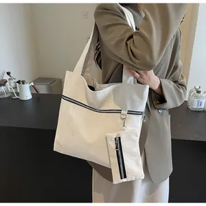 Detail view of the cream-white tote bag with textured fabric and small zipper pouch