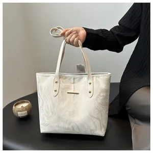 Detail of cream marble tote bag featuring gold hardware and elegant wavy print patterns