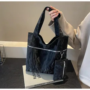Detail of black wrinkled tote bag featuring silver zipper and detachable mini pouch