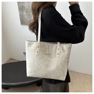 Detailed view of white marble pattern tote bag with gold hardware on model's shoulder