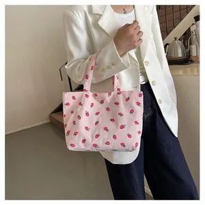 Détail du sac fourre-tout en velours rose avec imprimé fraise porté par un mannequin