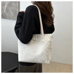 Detail of elegant marble pattern tote bag featuring gold hardware and slim handles