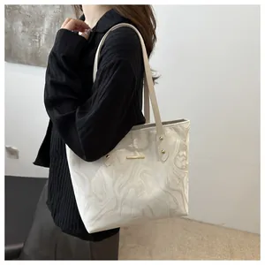 Detail of white marble print tote bag with gold metal clasp and premium leather texture