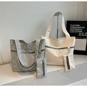 Detail of a minimalist crinkled tote bag set with matching zipper pouch on a stand