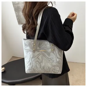 Grey marble texture tote bag with gold rivets and long strap shown as crossbody