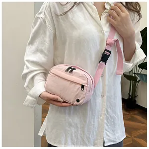 Detail of light pink nylon crossbody waist bag with dual zippers and adjustable strap