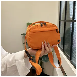 Detail of bright orange waterproof nylon shoulder bag with adjustable strap and metal zippers