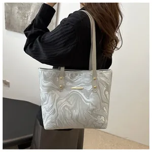 Close-up of a silver tote bag with marble texture and metallic finish on a model shoulder