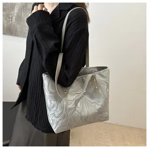 Detail of elegant silver ripple pattern tote bag with slim straps on a model wearing black