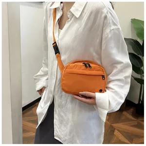 Detail of bright orange crossbody waist bag featuring durable nylon fabric and plastic buckle