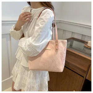 Detail of pink marble pattern tote bag with metallic bar and shoulder strap on a model
