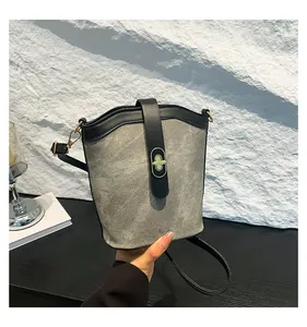 Detail of grey and black color-block bucket bag with elegant golden oval twist lock