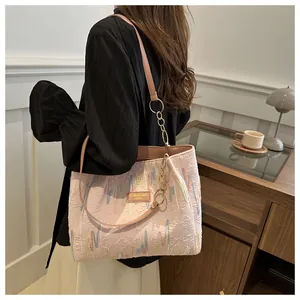 Detalle del bolso rosa texturizado con bordado, logo de cuero y correa de cadena dorada