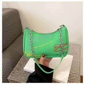 Dettaglio borsa a mezzaluna verde neon con catena d'argento e stampa graffiti chic