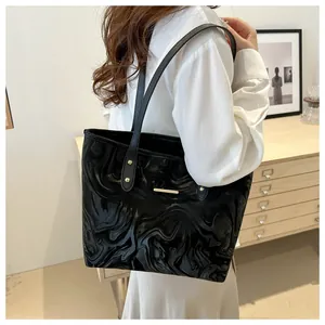 Close-up of black tote bag with marble texture and gold metal studs worn by a model