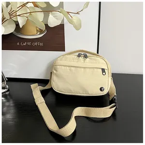 Close-up of the beige nylon small crossbody bag with adjustable strap and front zipper