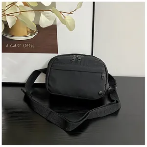 Detail of black nylon crossbody bag with adjustable strap on dark wooden table surface