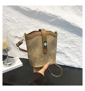 Detail of vintage khaki bucket bag featuring golden turn-lock and premium matte texture