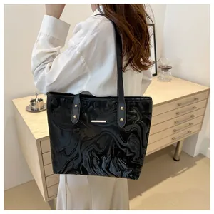 Detail of the black marbled tote bag showing glossy texture and slim shoulder straps
