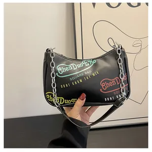 Dettaglio borsa a mezzaluna nera in pelle PU con graffiti colorati e tracolla a catena argento