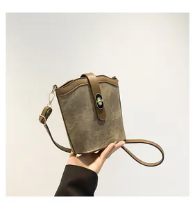Macro shot of the brown matte suede bucket bag showing contrast trim and turn-lock