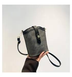 Detail of color-block bucket bag with gold twist lock and grey suede texture