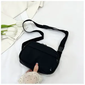 Detail of a black nylon square crossbody bag with adjustable strap and buckle closure