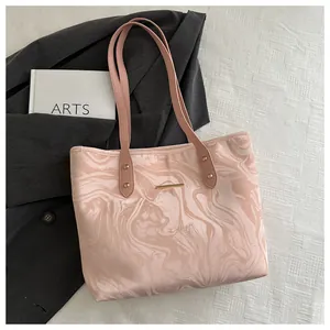 Detailed close-up of marble pattern on pink tote bag with elegant gold metal logo bar