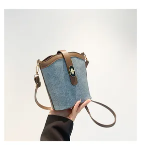 Detail of blue-grey felt bucket bag featuring brown leather trim and golden twist lock