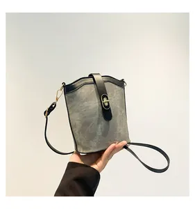 Detailed close-up of a grey suede bucket bag featuring a golden oval twist lock closure