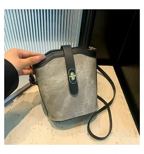 Detail view of contrast color bucket bag with gold turn-lock and grey matte texture