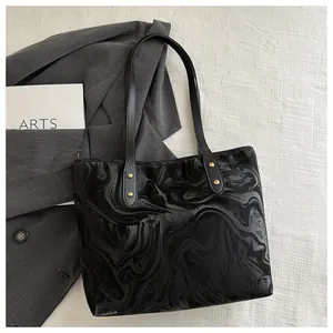 Detail view of large black tote bag with liquid marble texture and gold metal studs