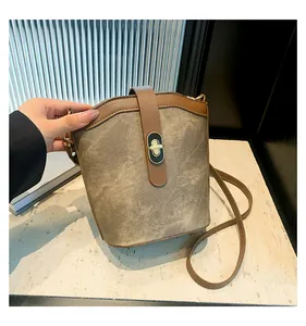 Detail of contrast stitching bucket bag with metal turn-lock and brown leather strap