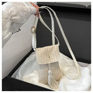 Detail of hand-woven straw crossbody bag with fringe tassel and adjustable strap
