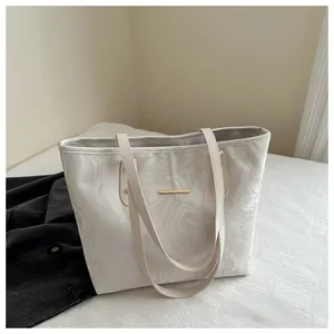 Detail of cream tote bag featuring marble ripple patterns and elegant gold metal trim