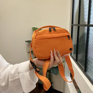 Vibrant orange nylon crossbody bag with adjustable strap and dual zipper compartments