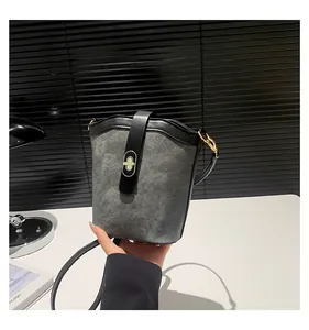 Close-up of contrast grey bucket bag with black leather straps and gold twist lock