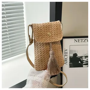 Detail of hand-woven straw crossbody phone bag with golden buckle and fringe tassel