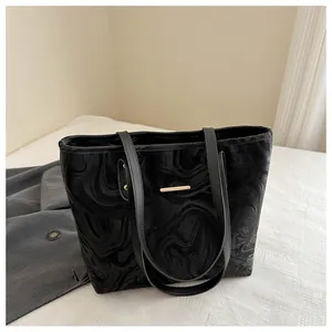 Detailed view of black tote bag with marble pattern and elegant gold metal bar accent