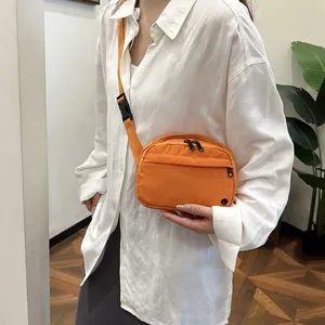 Orange nylon crossbody bag with dual zippers and adjustable strap for casual daily use